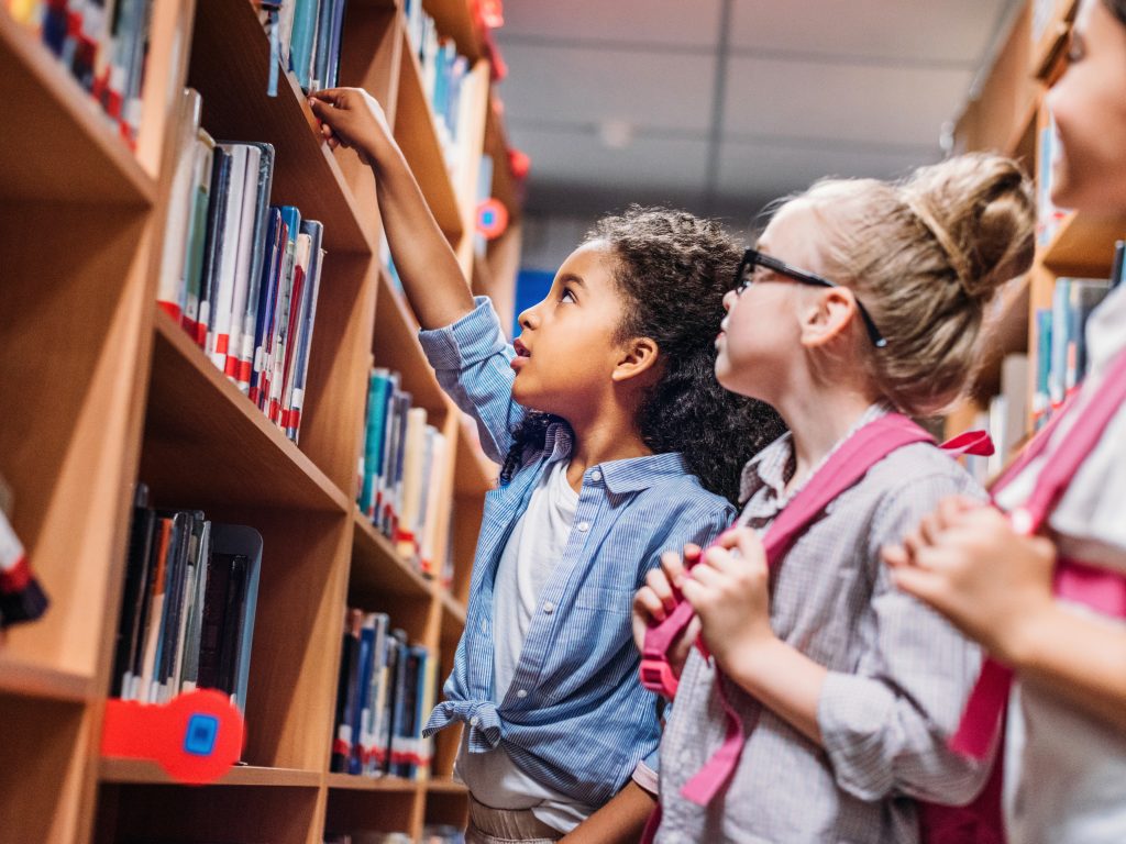 Young girl grabbing a book from the library