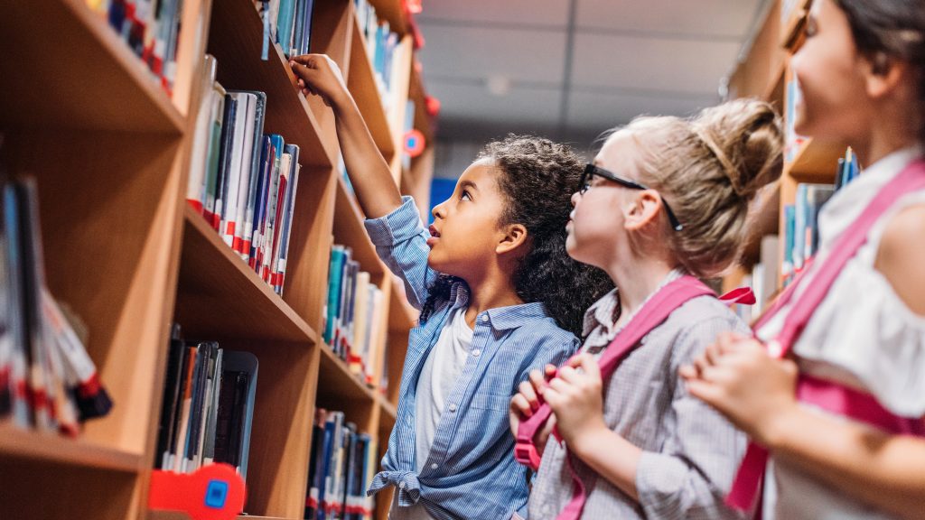 Young girl grabbing a book from the library