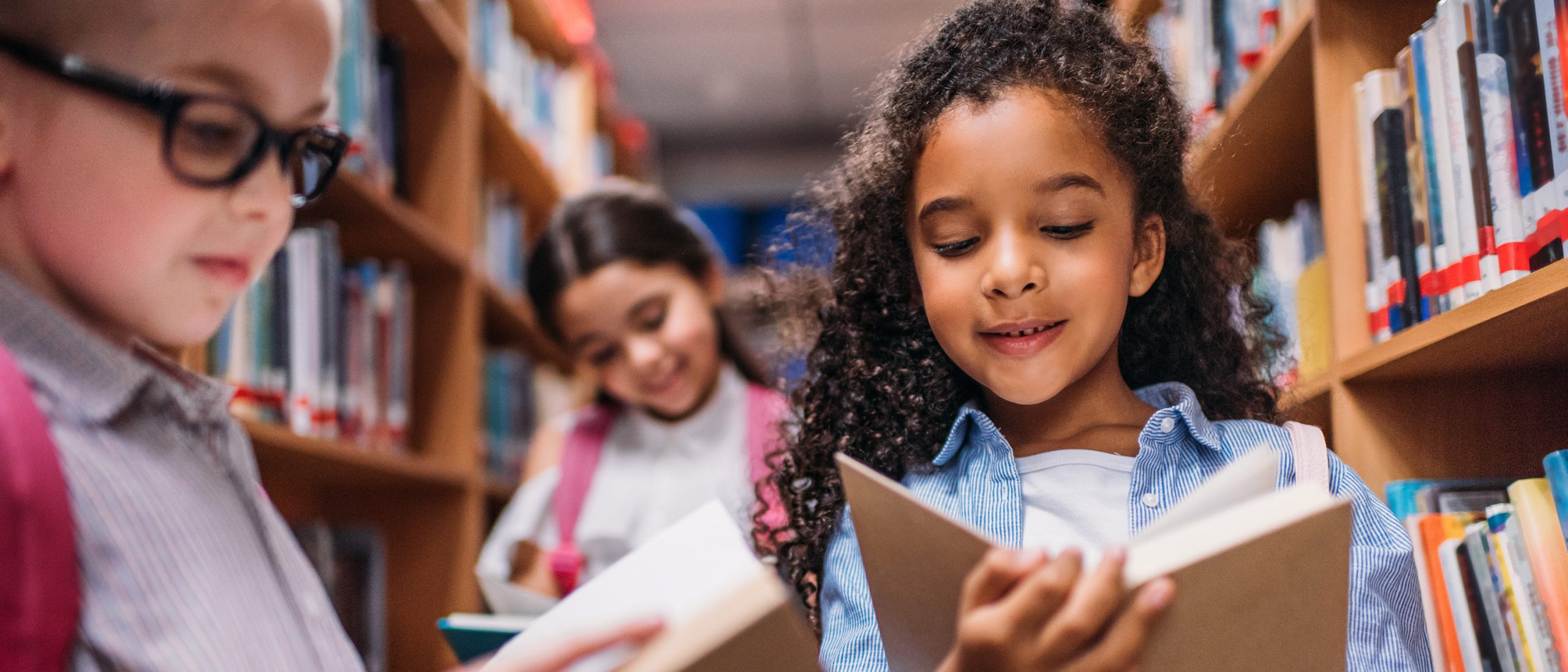 Young girl reading book in library