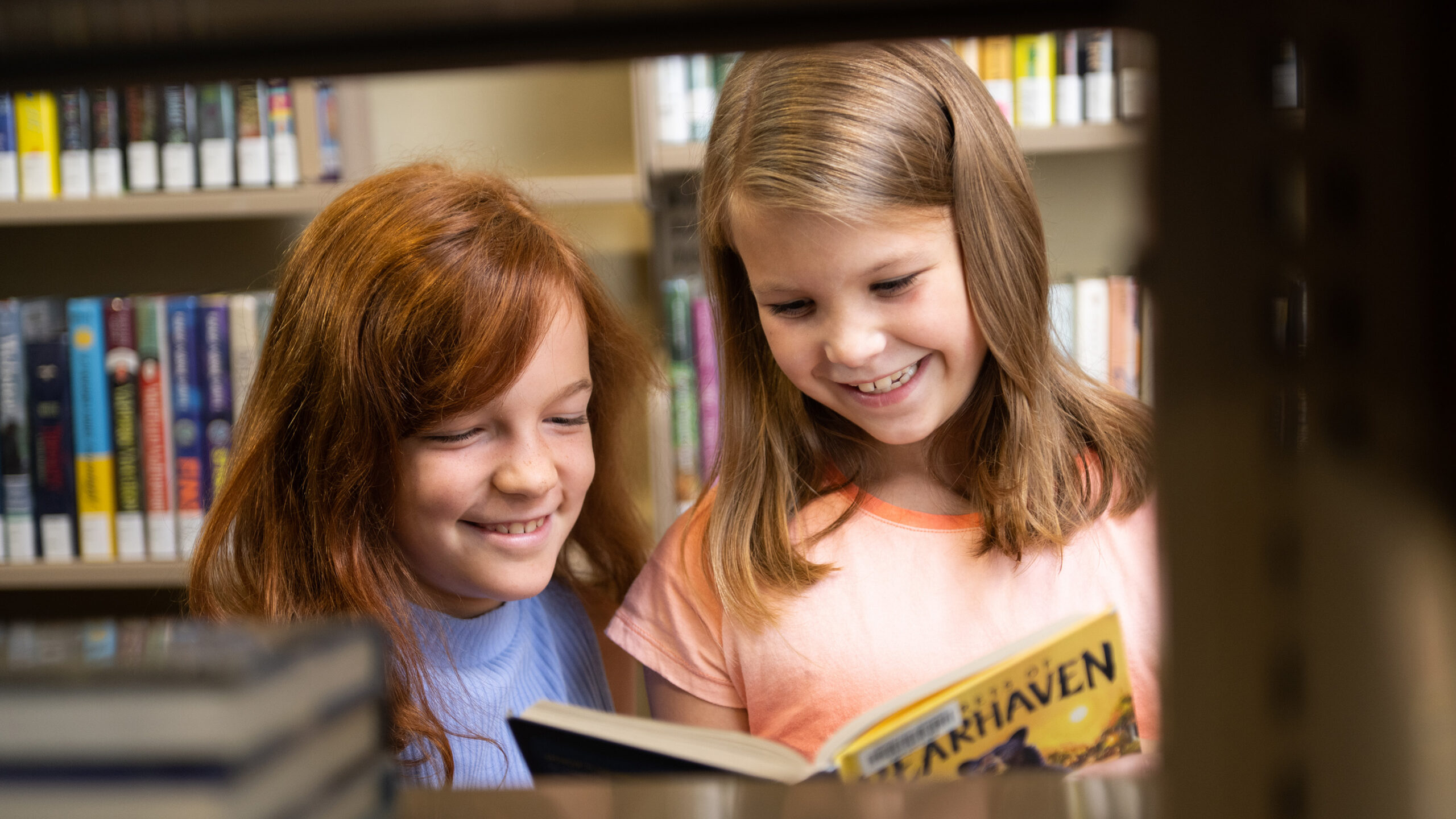 Two young girls reading in a library